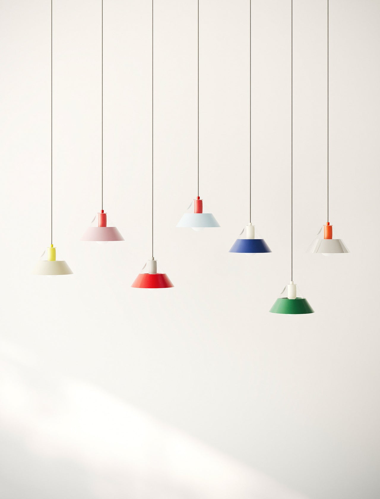 FIFTY FIFTY Lamp with red and pink metal shades hanging over a red table in a minimalist setting.