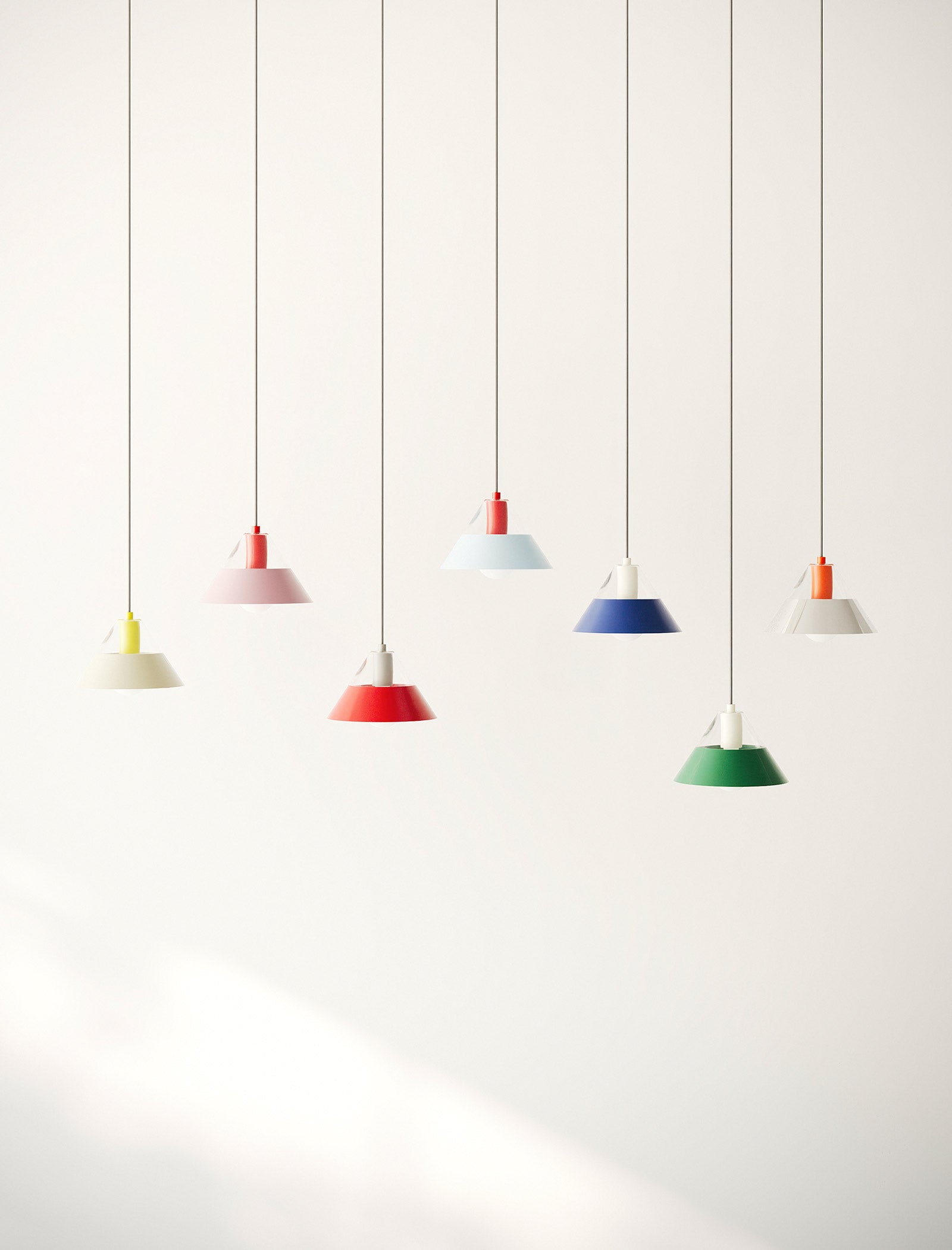 FIFTY FIFTY Lamp group of seven colorful pendant lamps with metal shades hanging against a white wall.