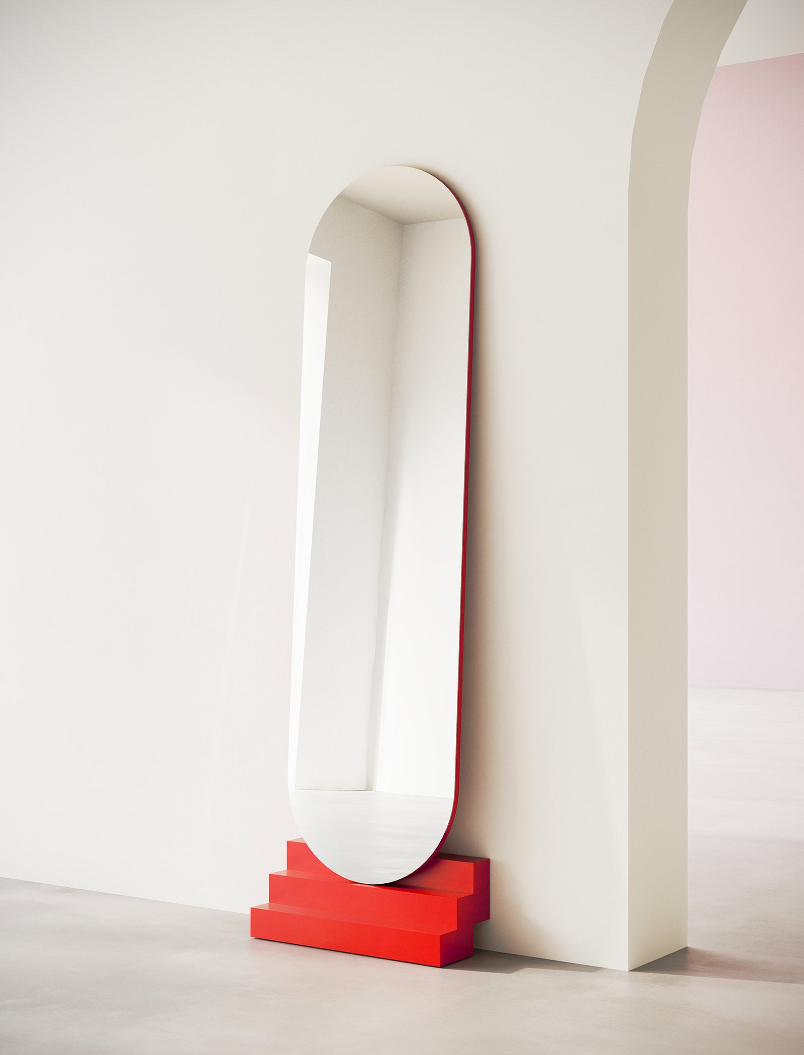 NONCHALANT Mirror L leaning against wall with vibrant red base in a minimalist modern interior setting